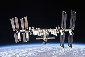 la station spatiale Internationale et au loin l'atmosphère terrestre